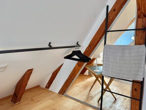 Ein Zimmer mit Holzboden, einem schwarzen Metallregal und einem weißen Handtuch, das an einer Metallstange hängt.