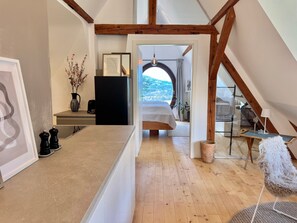 A modern kitchen with a wooden ceiling, a dining area with a white chair, and a view of a balcony. - Apartment 'In den Bäumen' – Quiet Apartment on the Edge of the Forest near Freiburg (Bollschweil)
