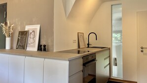 Cozinha moderna com forno embutido, pia e porta para uma varanda.