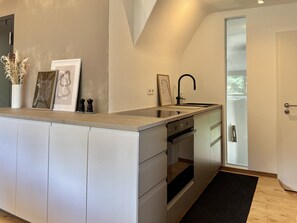 Eine moderne Küche mit Einbauofen, Spüle und einer Tür zum Balkon.