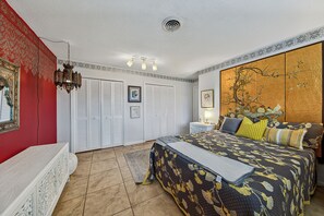 Ein Schlafzimmer mit einem Bett, einem Nachttisch, einer Lampe, einem Kleiderschrank und einer Wandverkleidung.