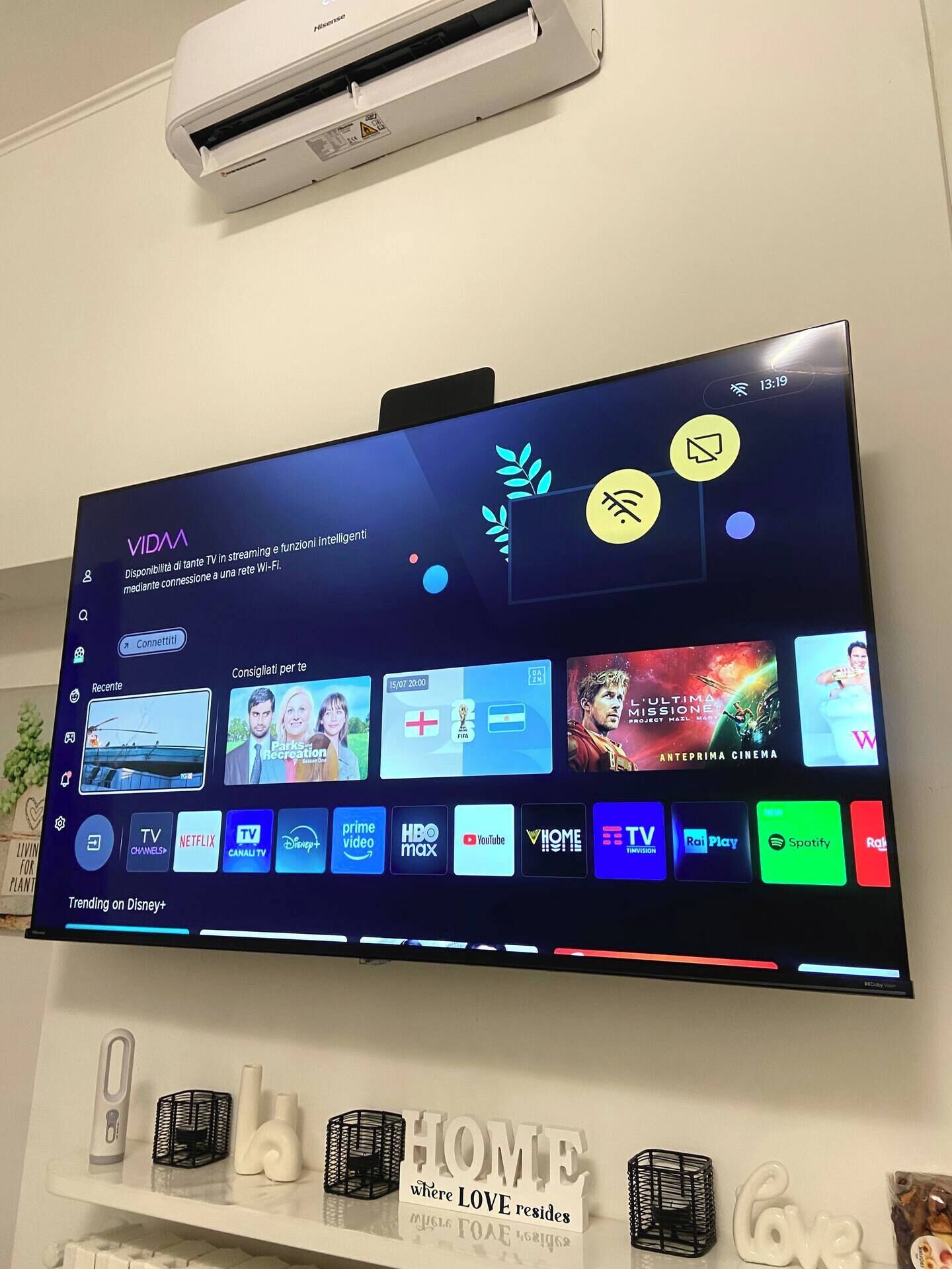 A flat-screen TV mounted on a wall displaying a streaming service interface with various entertainment options.