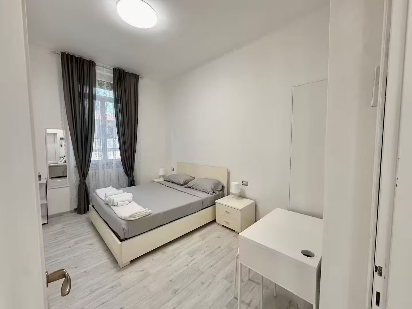 Une chambre à coucher moderne avec un lit, des tables de chevet, un miroir et une armoire.