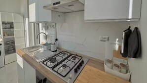 A modern kitchen with white cabinets, a gas stove, a sink, and a countertop.