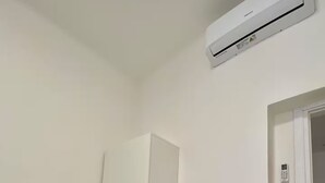 A room with a white desk, a chair, and an air conditioning unit on the wall.