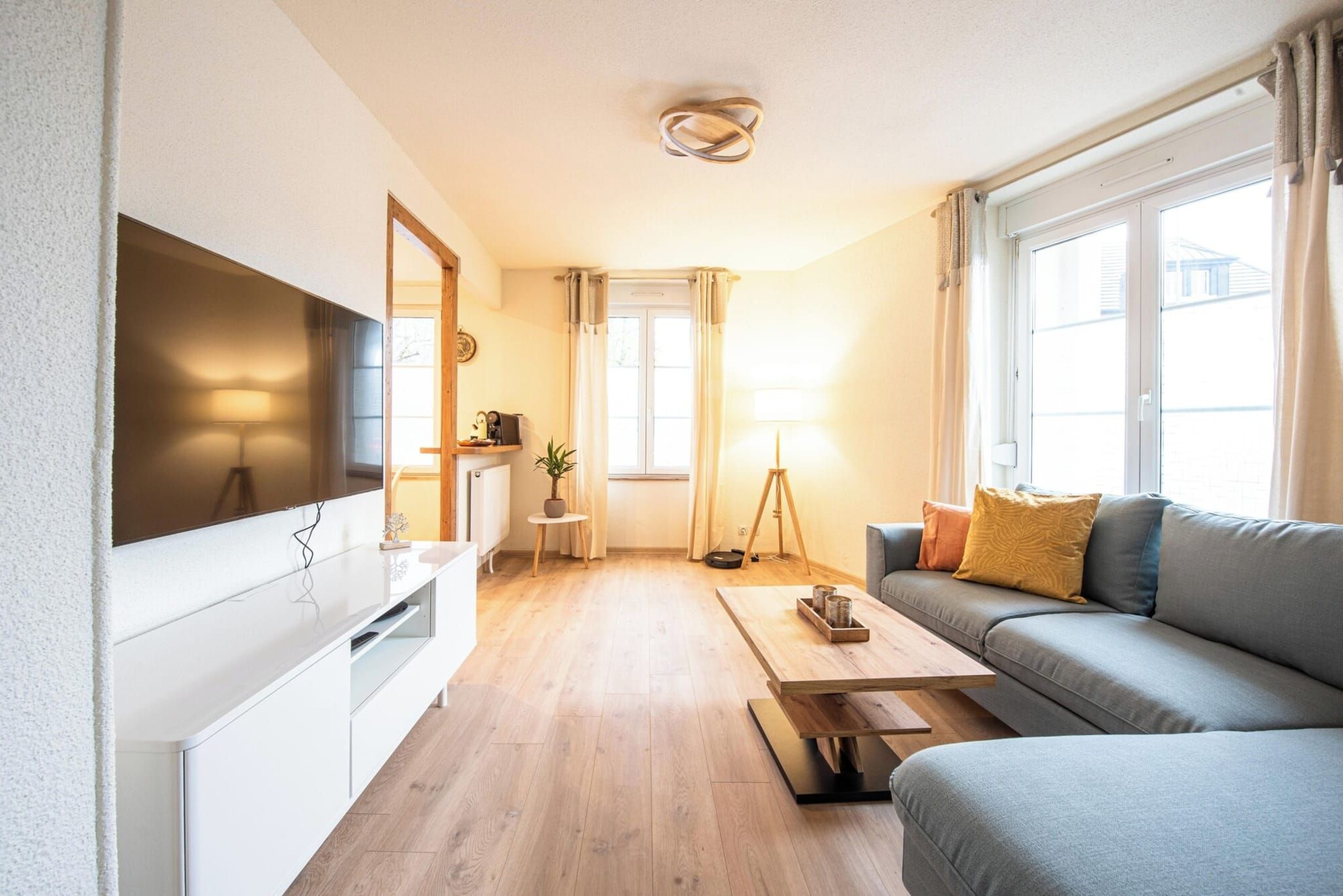 A modern living room with a flat-screen TV, a sofa, a coffee table, and a lamp.