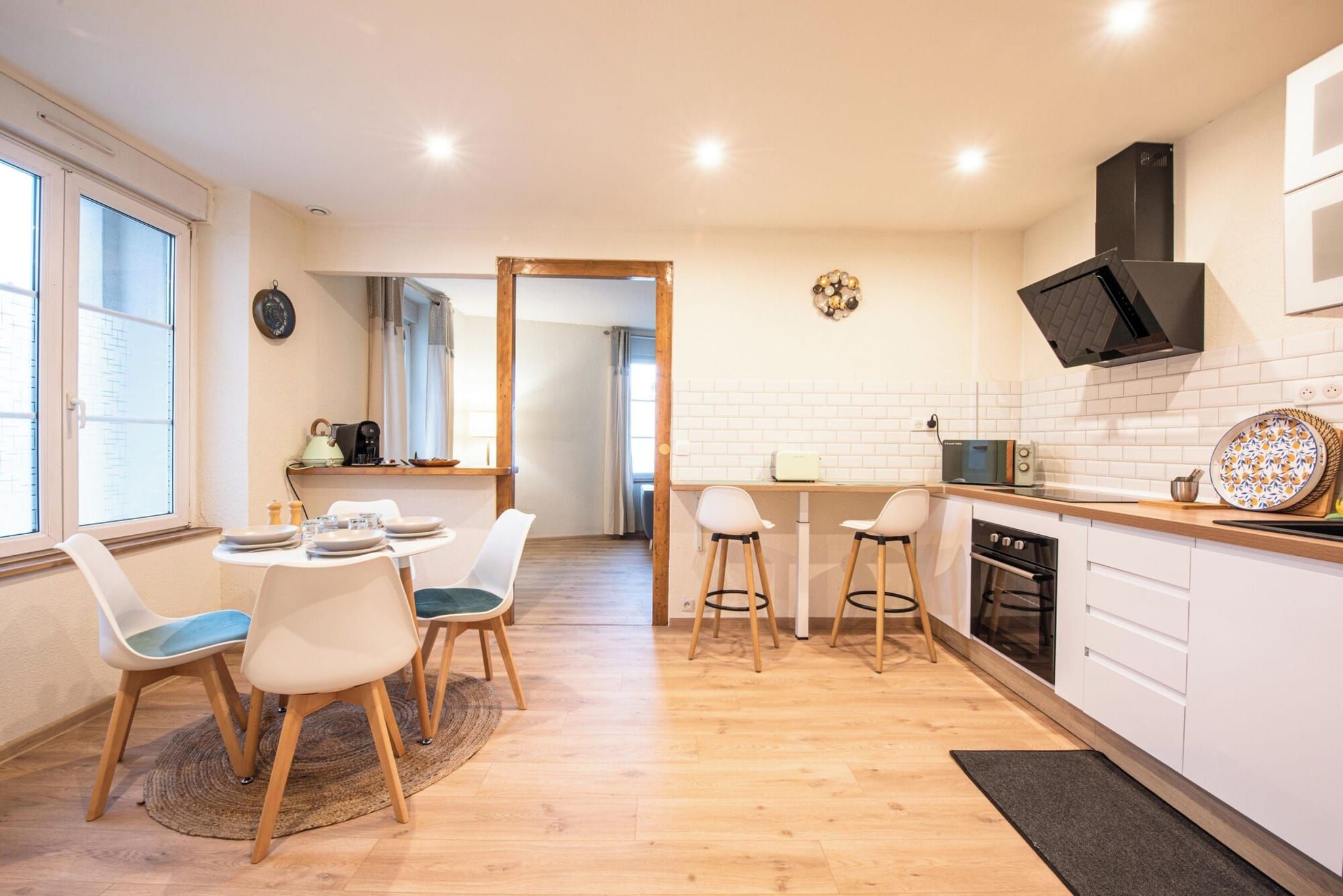 Une cuisine moderne avec des meubles blancs, un four à micro-ondes et une cuisinière. On y trouve également un coin repas avec une table et des chaises.