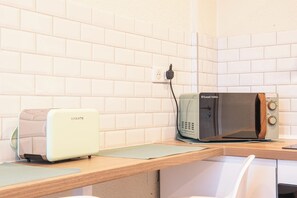 A kitchen with a white brick backsplash, a toaster, a kettle, and a microwave on a wooden countertop. - Mulhouse by Hardt (Mulhouse)
