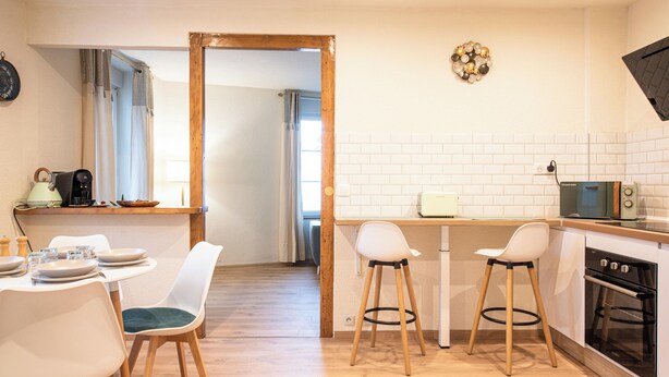 Una cocina moderna con azulejos blancos tipo metro, una mesa de comedor de madera con sillas, un microondas y un horno.