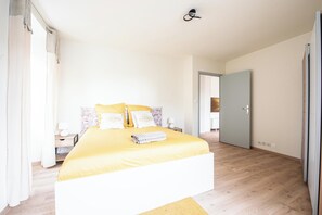 Ein Schlafzimmer mit einem Bett, Nachttischen, einer Wandleuchte und einer Tür.