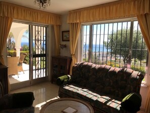 A living room with a sofa, a coffee table, and a view of the outdoors through a large window.
