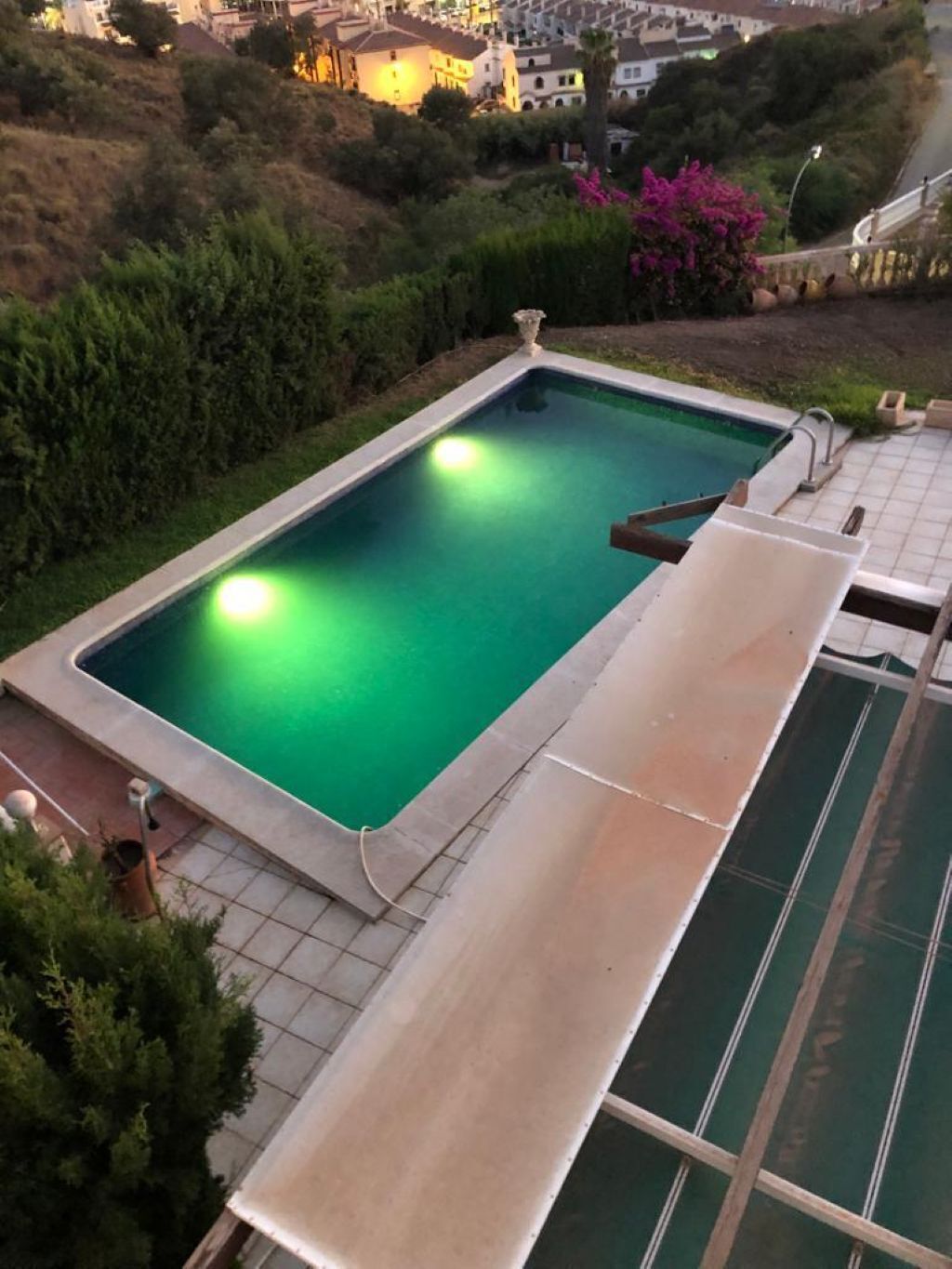 A rectangular swimming pool with a clear blue water surface, surrounded by a tiled deck area.