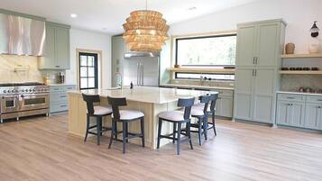 A modern kitchen with a central island, stainless steel appliances, and light-colored cabinetry.