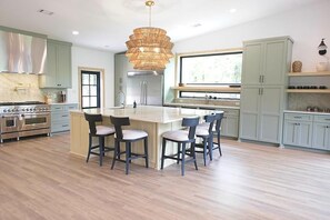 Una cocina moderna con una isla central, electrodomésticos de acero inoxidable y armarios de tonos claros.