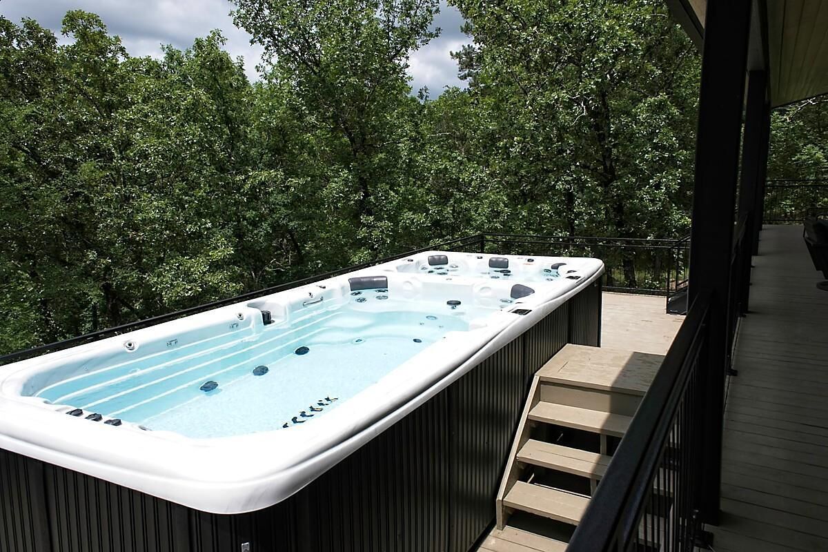 A hot tub on a wooden deck with a view of trees.