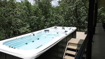 A hot tub on a wooden deck with a view of trees.