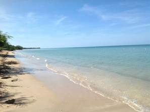 A beach with clear water, sandy shore, and sparse vegetation. - Enjoyable 2-bedroom apartment w/full AC in Combate. Pool, generator & water tank (Combate)