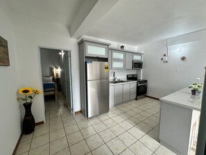 A compact kitchen with a refrigerator, microwave, stove, and sink. - Enjoyable 2-bedroom apartment w/full AC in Combate. Pool, generator & water tank (Combate)