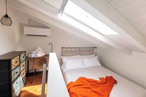 A bedroom with a sloped ceiling, a bed with white bedding, a wooden dresser with drawers, and a skylight. - La Mansarda in Oltretorrente, a cozy retreat among the rooftops of Parma (Parma)