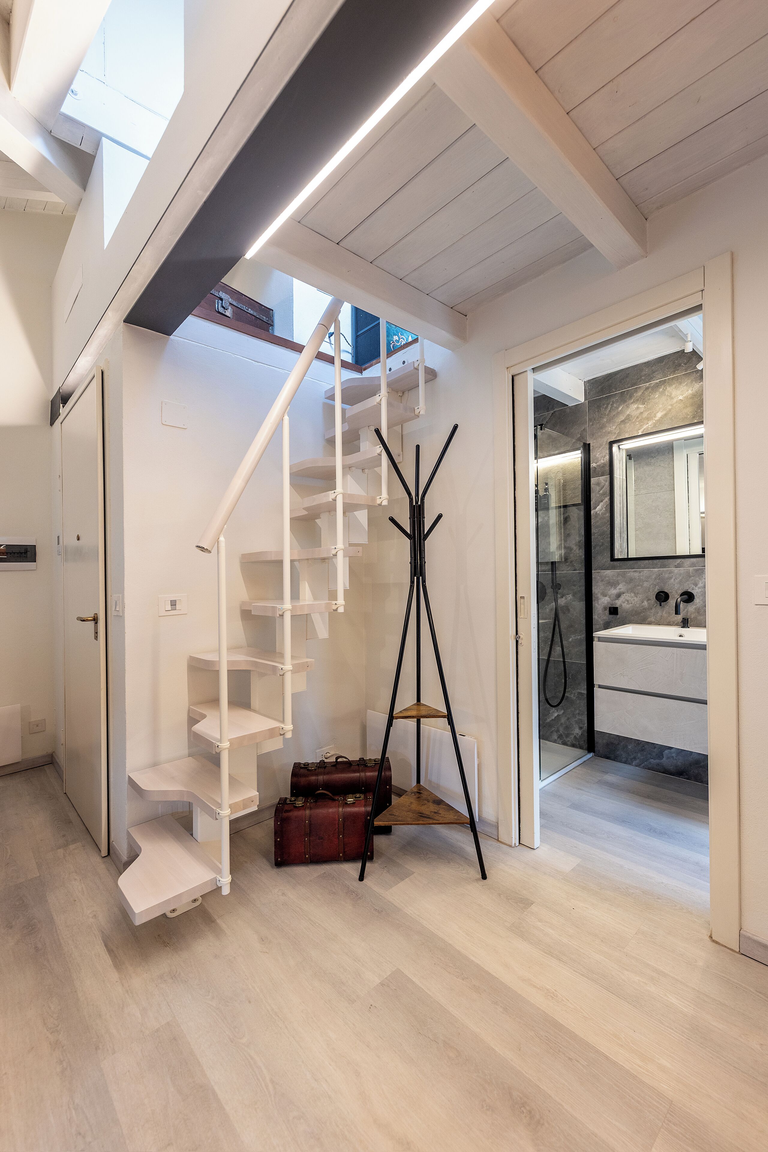 Un intérieur moderne avec un escalier, un porte-manteau et une salle de bain dotée d’un miroir.