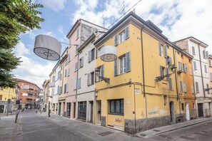 Straßenansicht mit mehrstöckigen Gebäuden, blauem Himmel und Fußgängern.