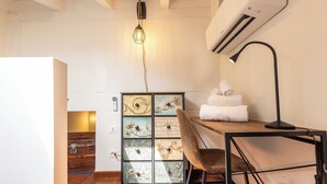 A compact room with a wooden table, a chair, a decorative cabinet, and a hanging light fixture. - La Mansarda in Oltretorrente, a cozy retreat among the rooftops of Parma (Parma)
