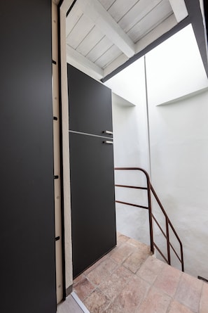A stairway leading to a dark door with a metal handle, a metal railing, and a tiled floor. - La Mansarda in Oltretorrente, a cozy retreat among the rooftops of Parma (Parma)