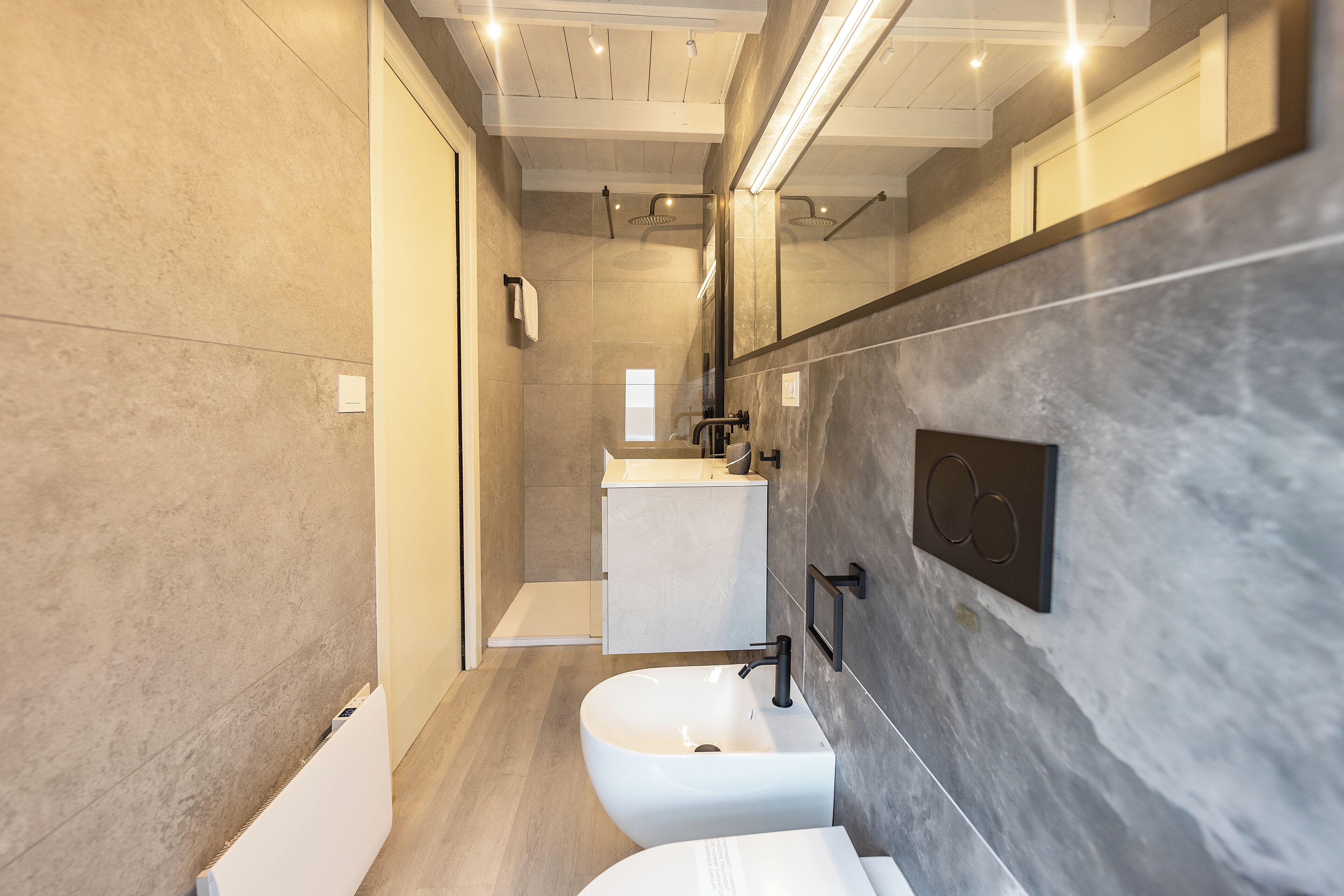 Ein modernes Badezimmer mit einem weißen Waschbecken, einem Spiegel und einer Duschkabine.