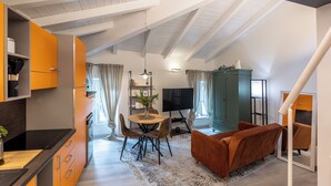 A modern kitchen with a dining area, a television, and a sofa. - La Mansarda in Oltretorrente, a cozy retreat among the rooftops of Parma (Parma)