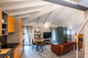 Eine moderne Küche mit Essbereich, Fernseher und Sofa.