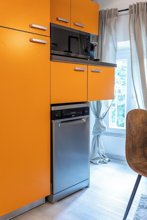 Eine kleine Küche mit Mikrowelle, Backofen und Kühlschrank.