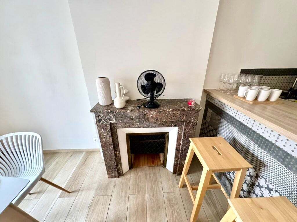 Una sala de estar moderna con chimenea, un ventilador, una mesa de madera y una silla.