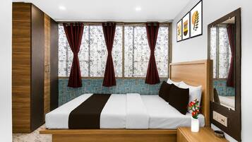 Una habitación de hotel con una cama, una mesita de noche, un espejo y una ventana con cortinas.