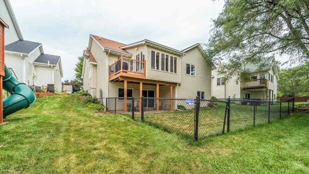Un quartier résidentiel avec des maisons, une cour clôturée et un toboggan vert.