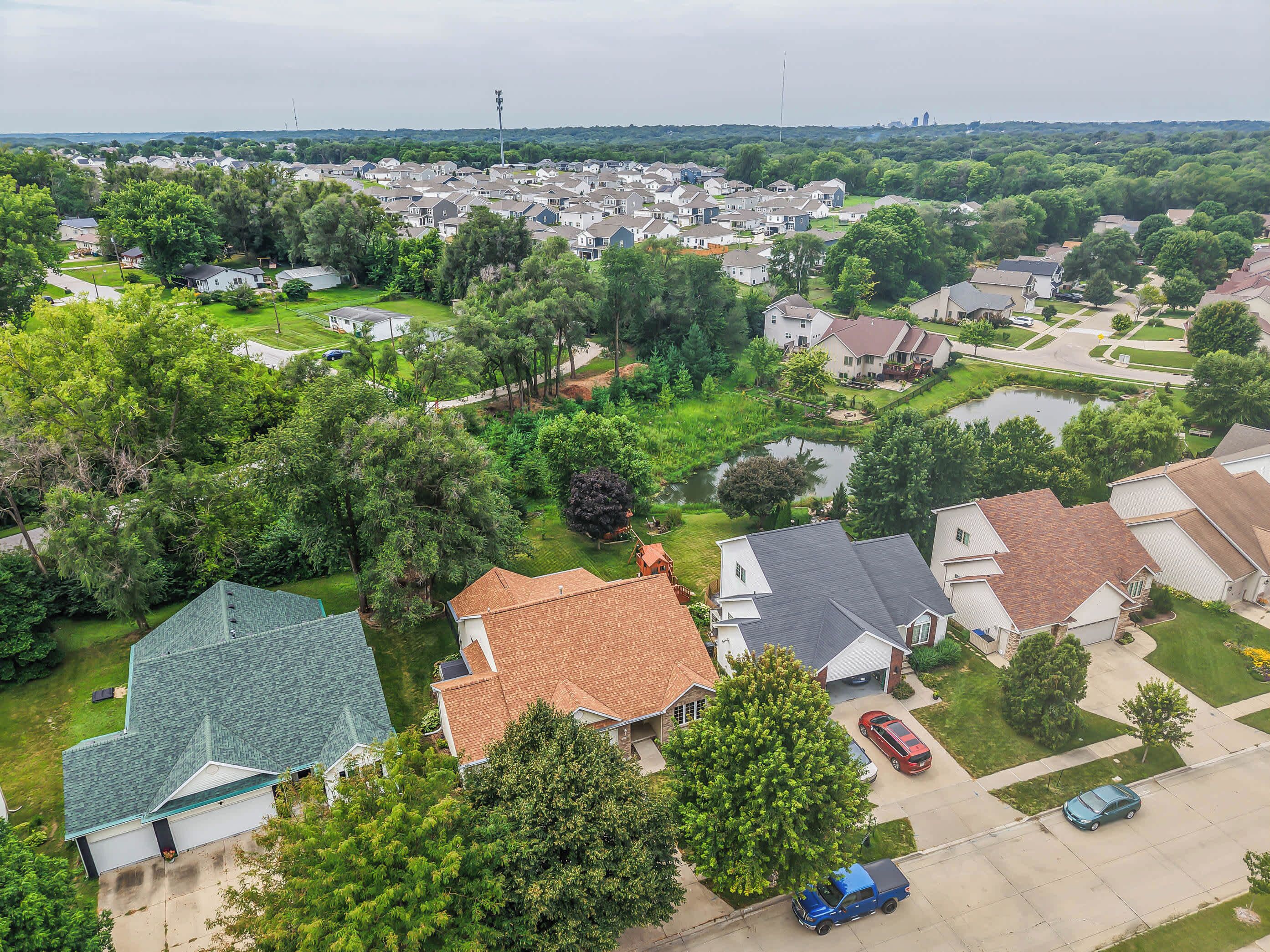 Un quartier résidentiel avec des maisons, un étang et un ciel dégagé.