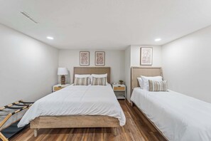 A hotel room with two beds, a wooden bench, and a nightstand with a lamp. - Sleeps 11, 4BR | Spacious Family Stay (Des Moines)