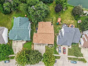 A residential area with houses, a driveway, and a body of water. - Sleeps 11, 4BR | Spacious Family Stay (Des Moines)