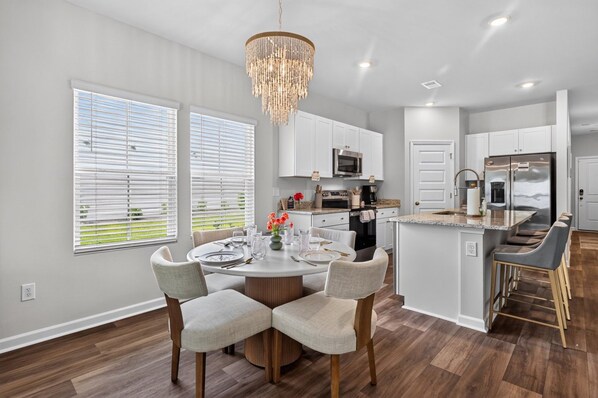 A modern kitchen with white cabinetry, a central island, and a chandelier.