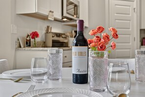 A dining table set with plates, cutlery, and glasses, with a bottle of wine and a vase of flowers.