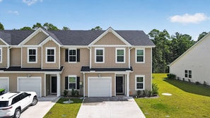 A two-story residential building with a garage on the ground floor and a driveway leading to the entrance.