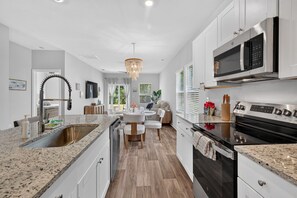 A modern kitchen with a central island, stainless steel appliances, and a chandelier.