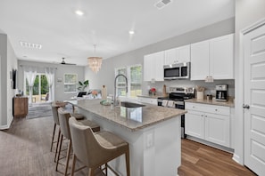 A modern kitchen with a central island, white cabinetry, and stainless steel appliances.