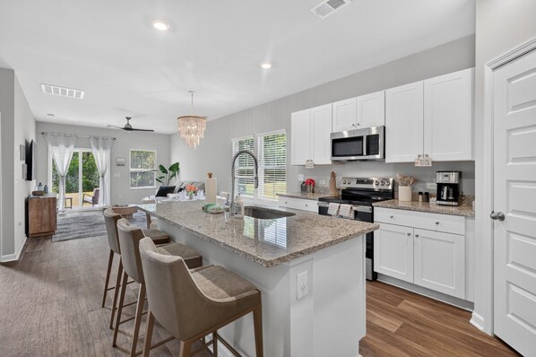 A modern kitchen with a central island, white cabinetry, and stainless steel appliances.