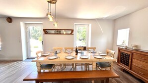 A dining area with a wooden table set for six, a bench, and a cabinet with drawers. - Les Pierres de Lamballe – Countryside near beaches (Lamballe)