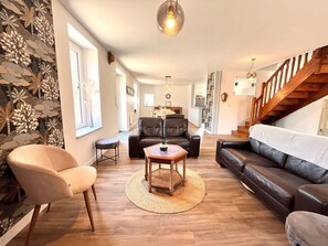 Ein Wohnzimmer mit Sofa, Sessel, Couchtisch und einer Treppe.