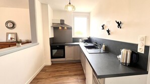 A modern kitchen with a black countertop, stainless steel appliances, and a pendant light. - Les Pierres de Lamballe – Countryside near beaches (Lamballe)