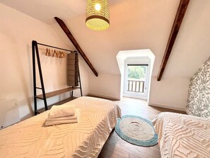 Ein Schlafzimmer mit zwei Betten, einer Leitern, einer Hängelampe und Blick ins Freie.