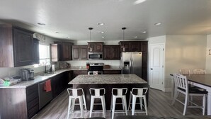 A modern kitchen with dark wood cabinets, stainless steel appliances, and a central island with bar stools. - Family and pet friendly 5-bedroom home in charming Clearfield (Clearfield)
