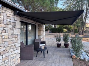 A covered patio with stone walls, wicker furniture, and potted plants. - A Cottage Amid the Birdsong. Beautiful views and tranquility, 300 meters from Flow Vélo (Chazelles)