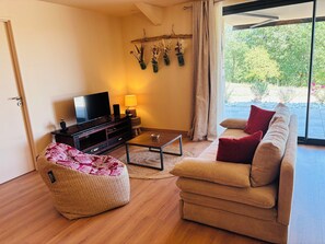A modern living room with a sofa, a bean bag, a coffee table, a TV, and a lamp. - A Cottage Amid the Birdsong. Beautiful views and tranquility, 300 meters from Flow Vélo (Chazelles)